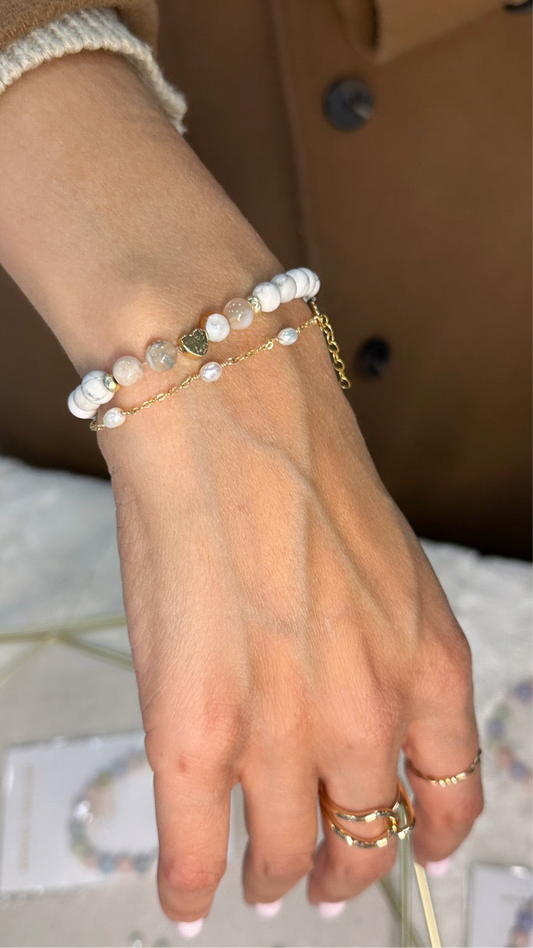 A person's hand wearing a gold-filled bracelet with white pearl.