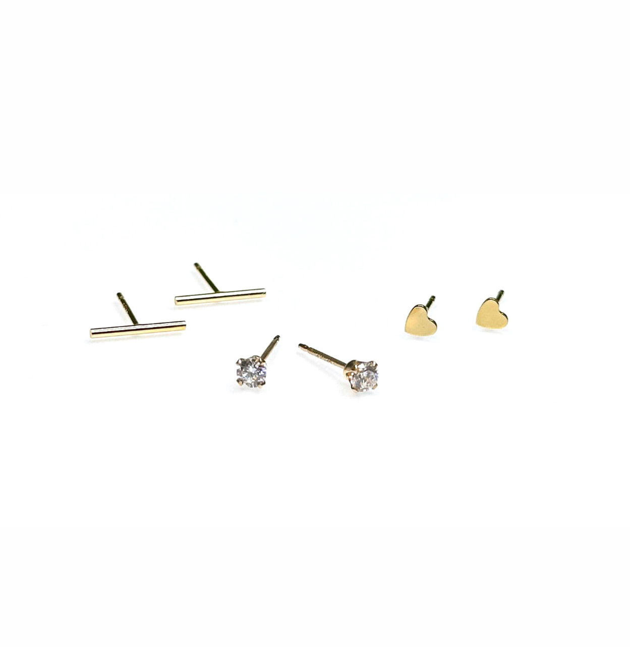 Three pairs of stud earrings, featuring minimalistic designs including bar, cubic zirconia accents, and heart shapes, all crafted from 14K gold-filled material.