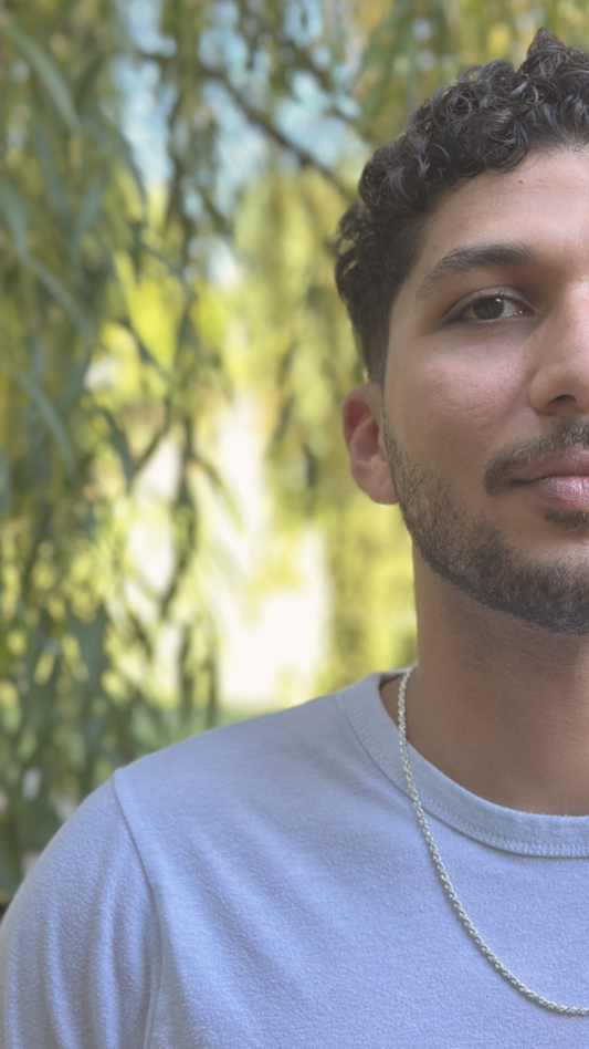 Man wearing a white shirt with a blurred green background