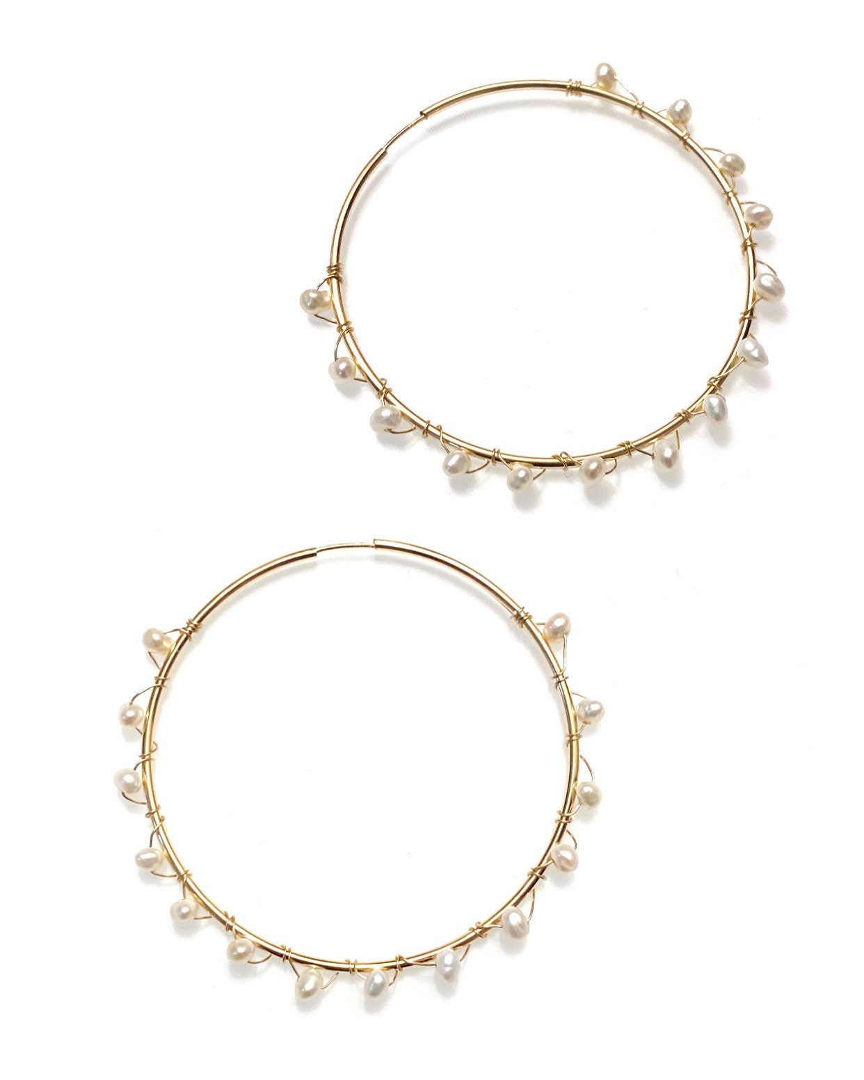 A pair of gold-filled hoop earrings with wrapped freshwater pearls around them.