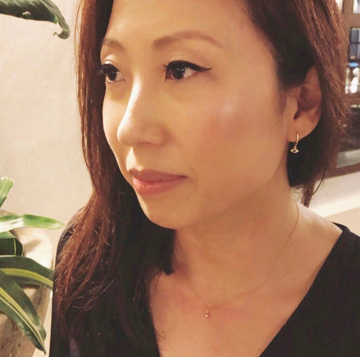 Close-up of evil eye huggie earrings showing white and blue CZ stone detail and protection charm design