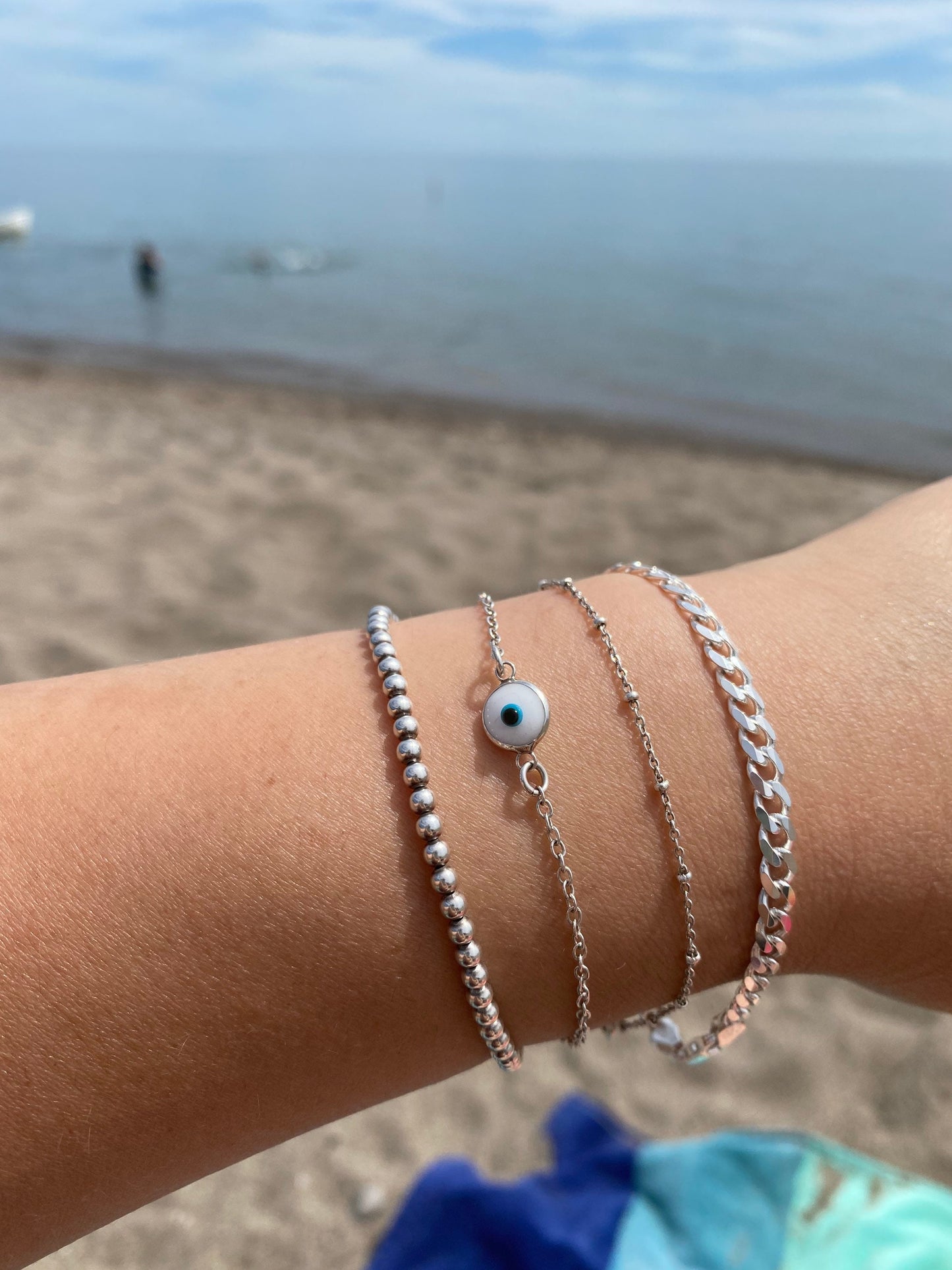 sterling silver curb chain bracelet stacked with ball evil eye and satellite chain bracelets