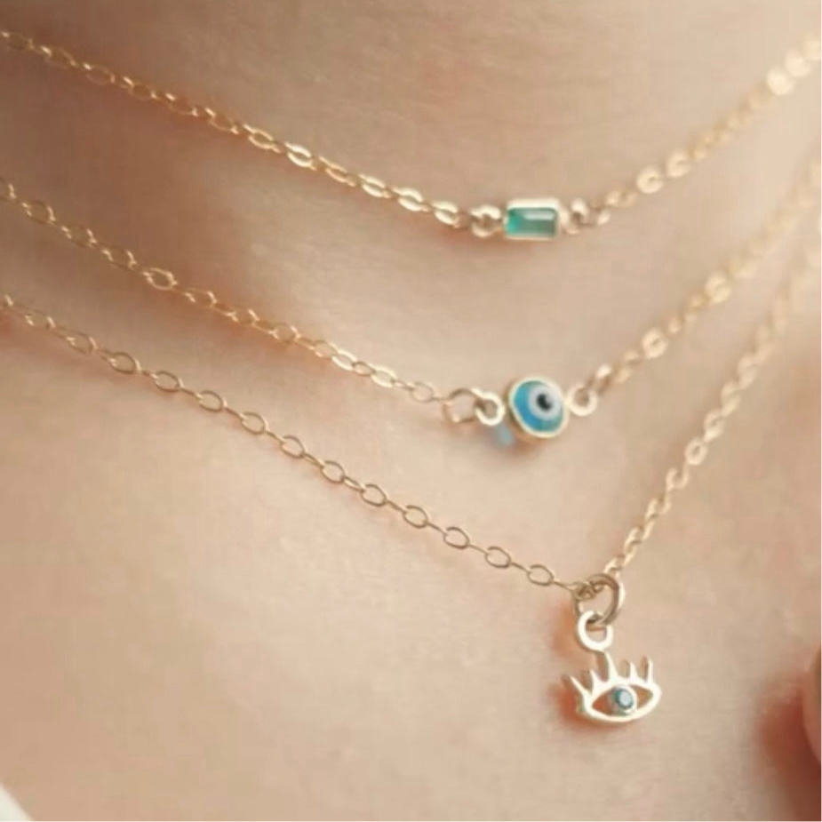 Close-up of layered gold necklaces with eye-shaped charms on a skin background