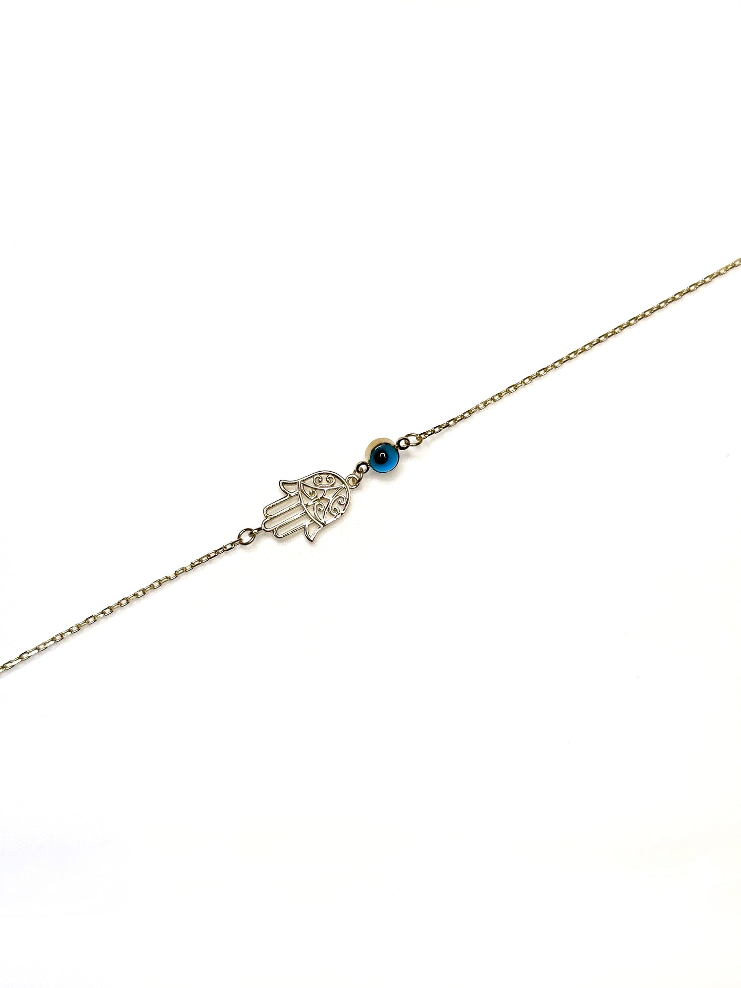 A gold bracelet featuring a Hamsa hand charm and a vibrant cobalt blue evil eye charm on a white background.