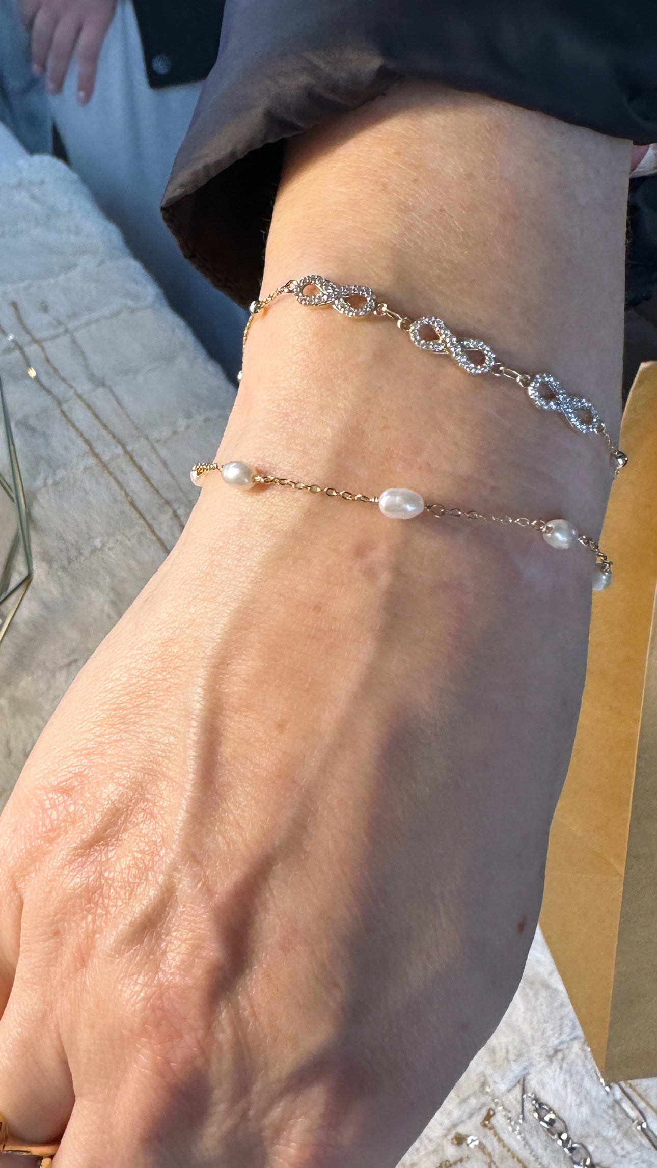 Close up of a person's hand wearing a gold-filled bracelet with white pearl.