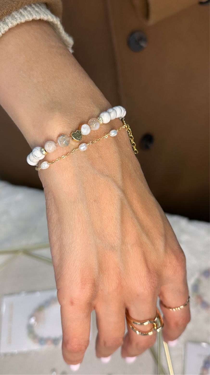 A person's hand wearing a gold-filled bracelet with white pearl.