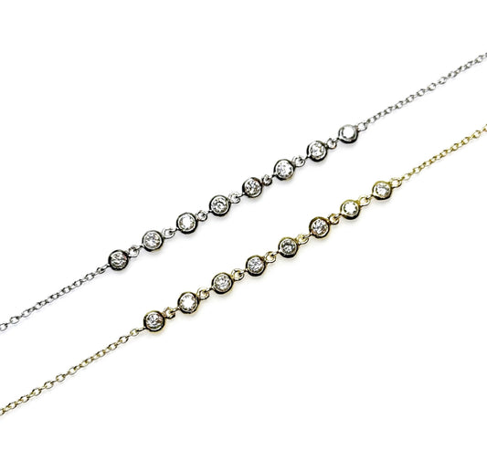 A two-layered dainty bracelet with eight bezel set cubic zirconia charms in a gold-plated sterling silver on a white background.