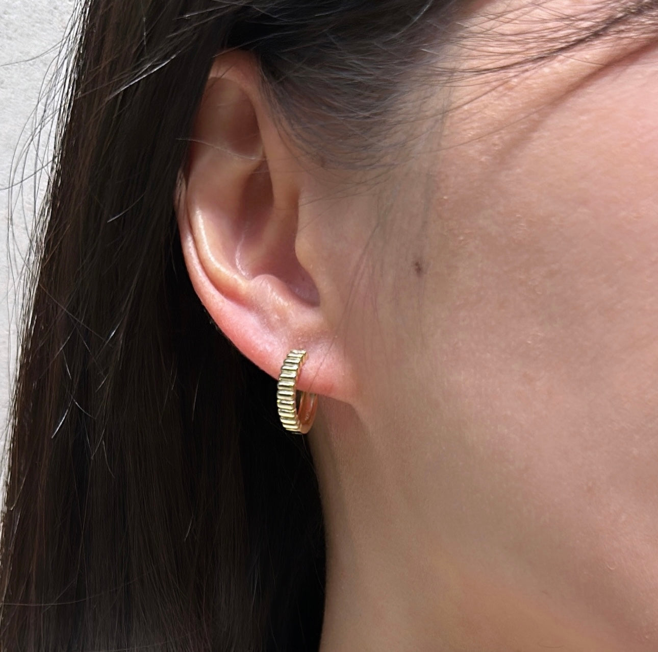 Ridged gold plated hoop earrings styled on model showing 15mm petite size