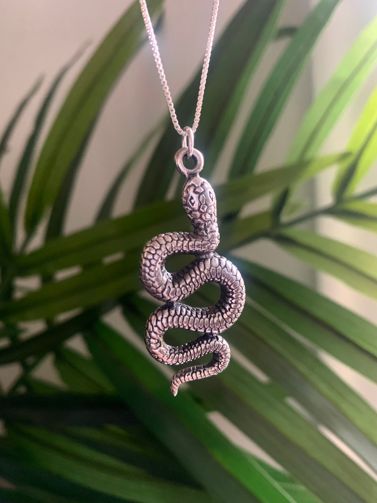 Snake pendant necklace against green background