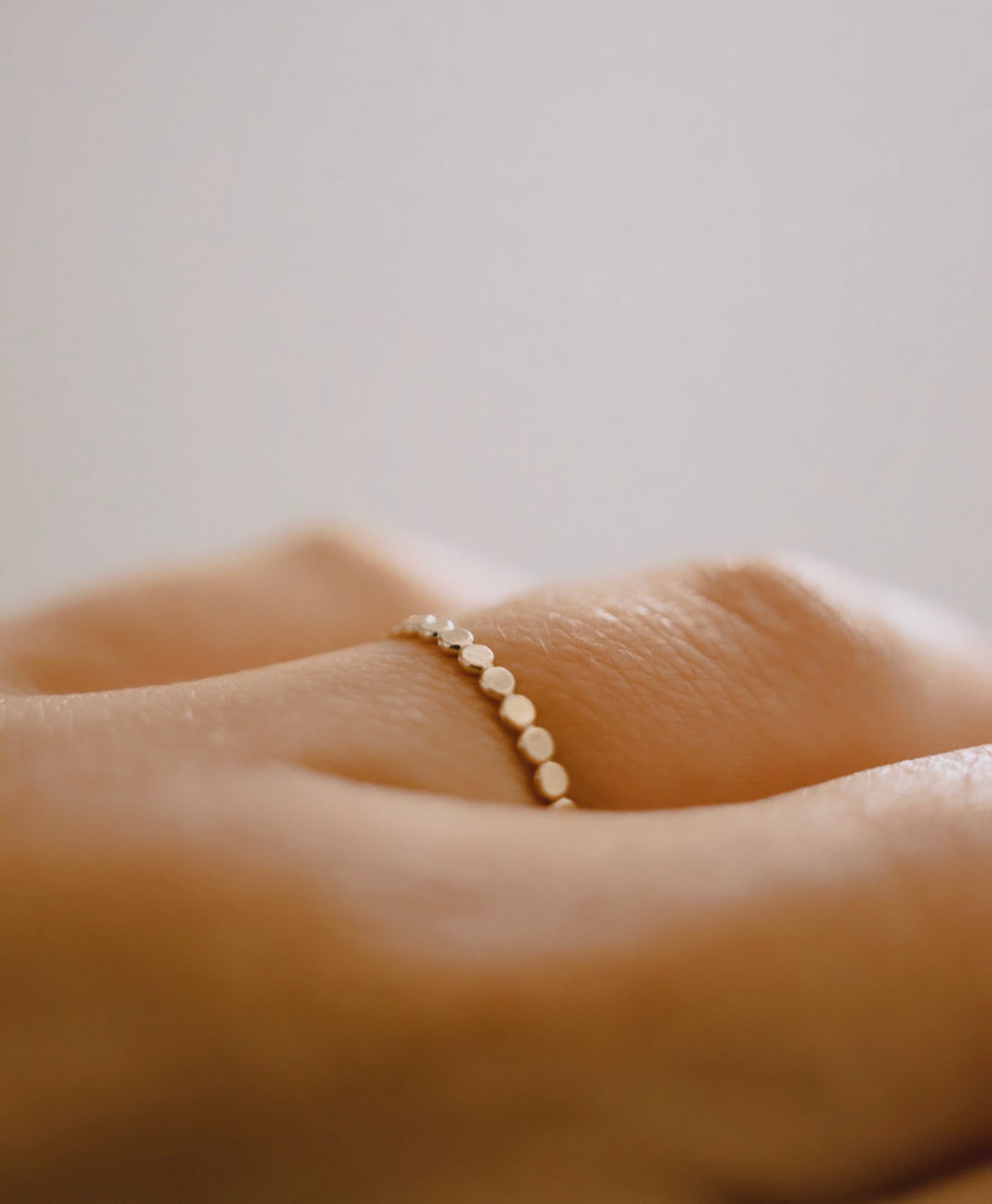 A close-up image of a person's hand wearing a 10K solid gold eternity ring.