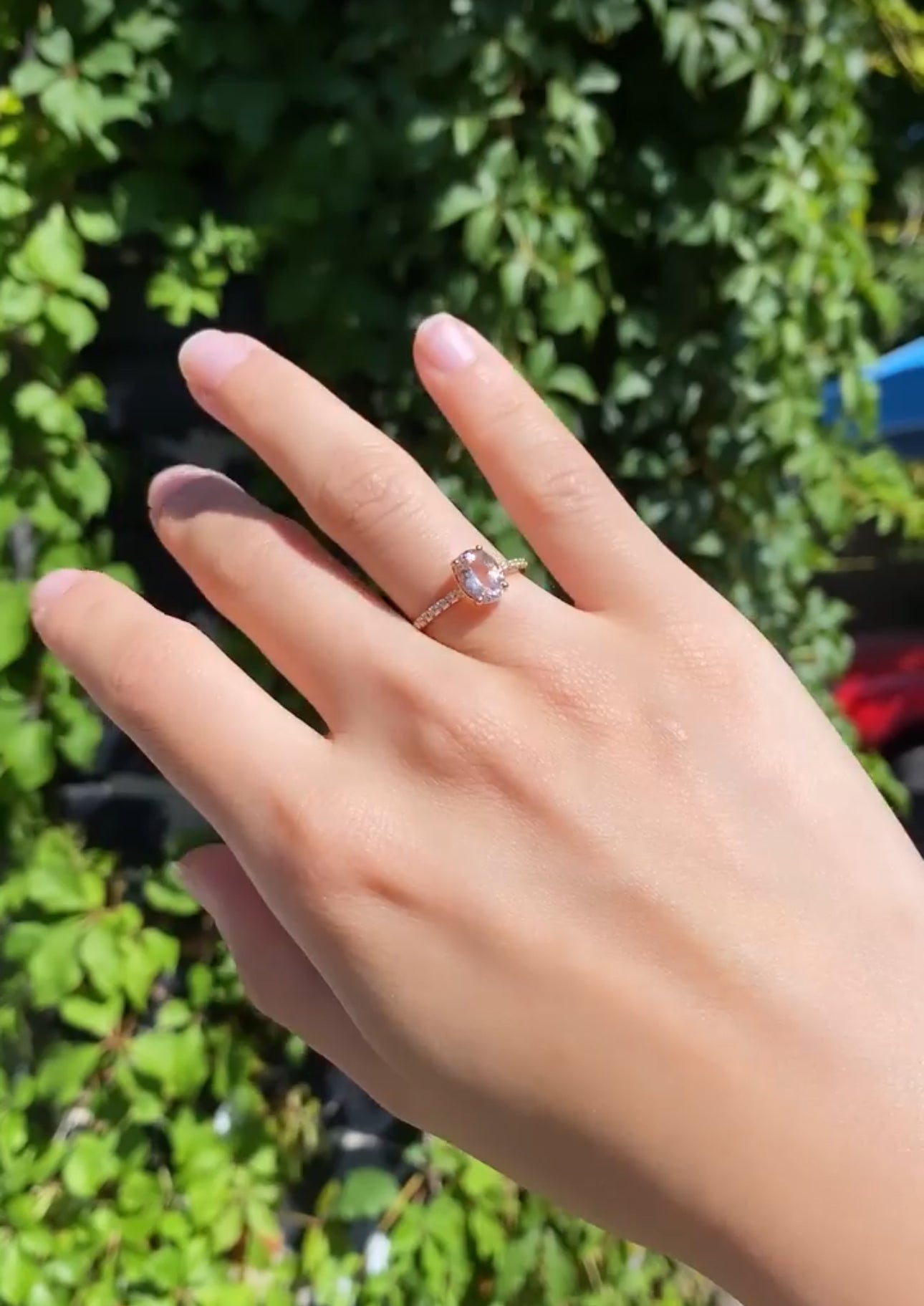Hand wearing a ring with a green leafy background
