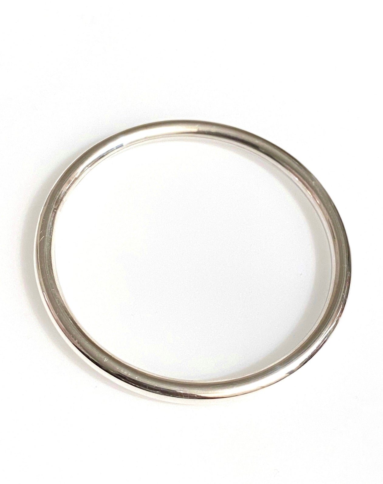 A sterling silver tube bangle bracelet against a white background.