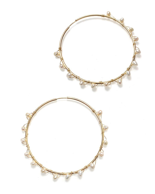 A pair of gold-filled hoop earrings with wrapped freshwater pearls around them.