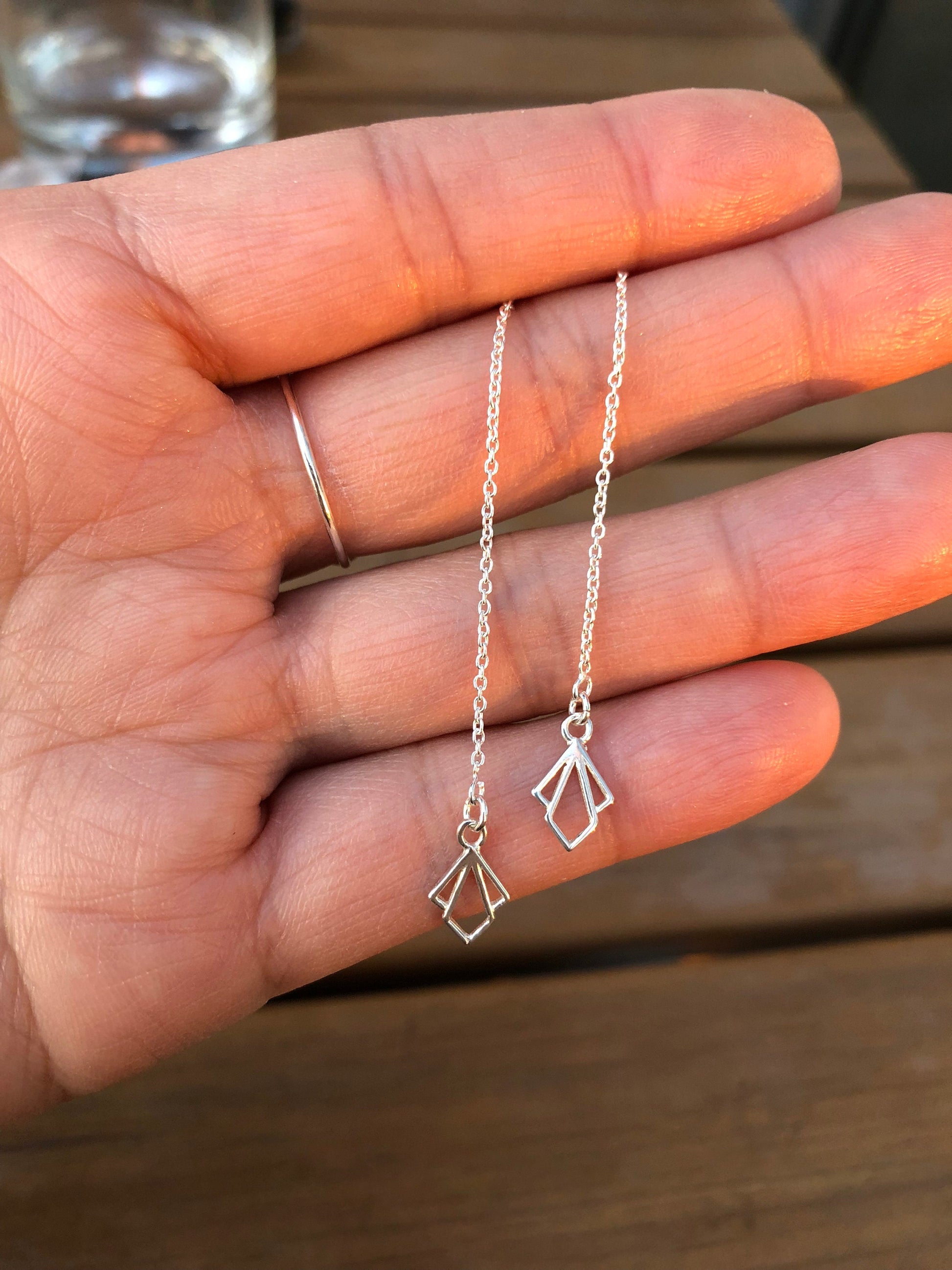 Close-up of sterling silver raindrop threader earrings showing delicate pendant and dramatic long back post