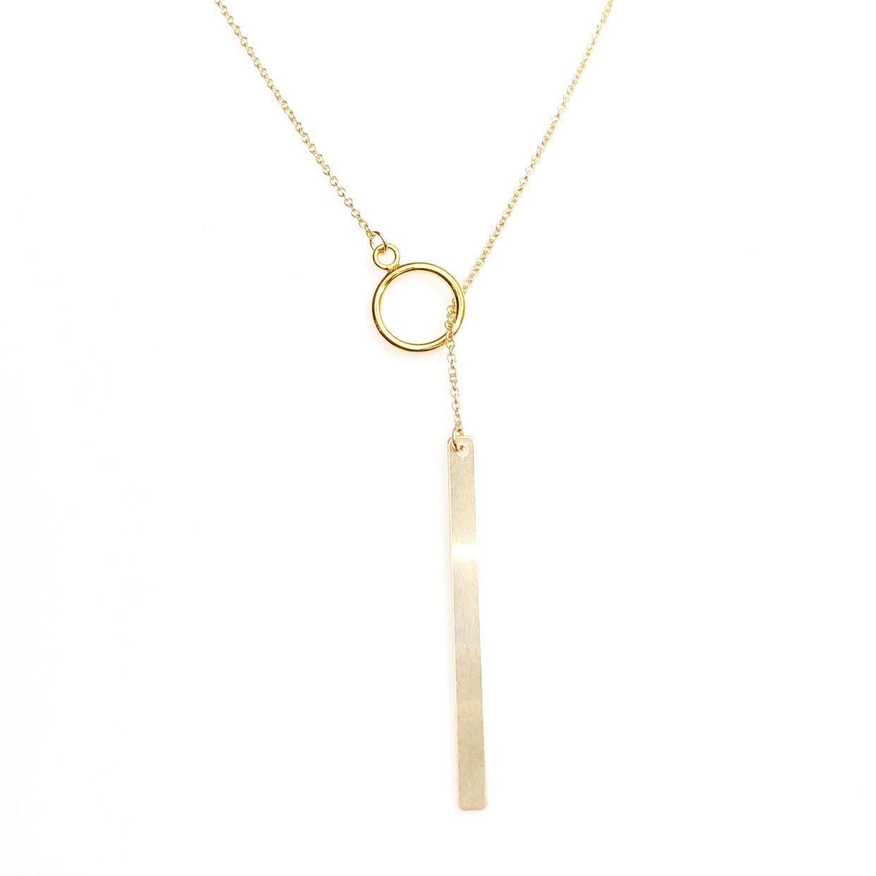 Close-up of signature lariat necklace showing bar pendant and circle closure detail