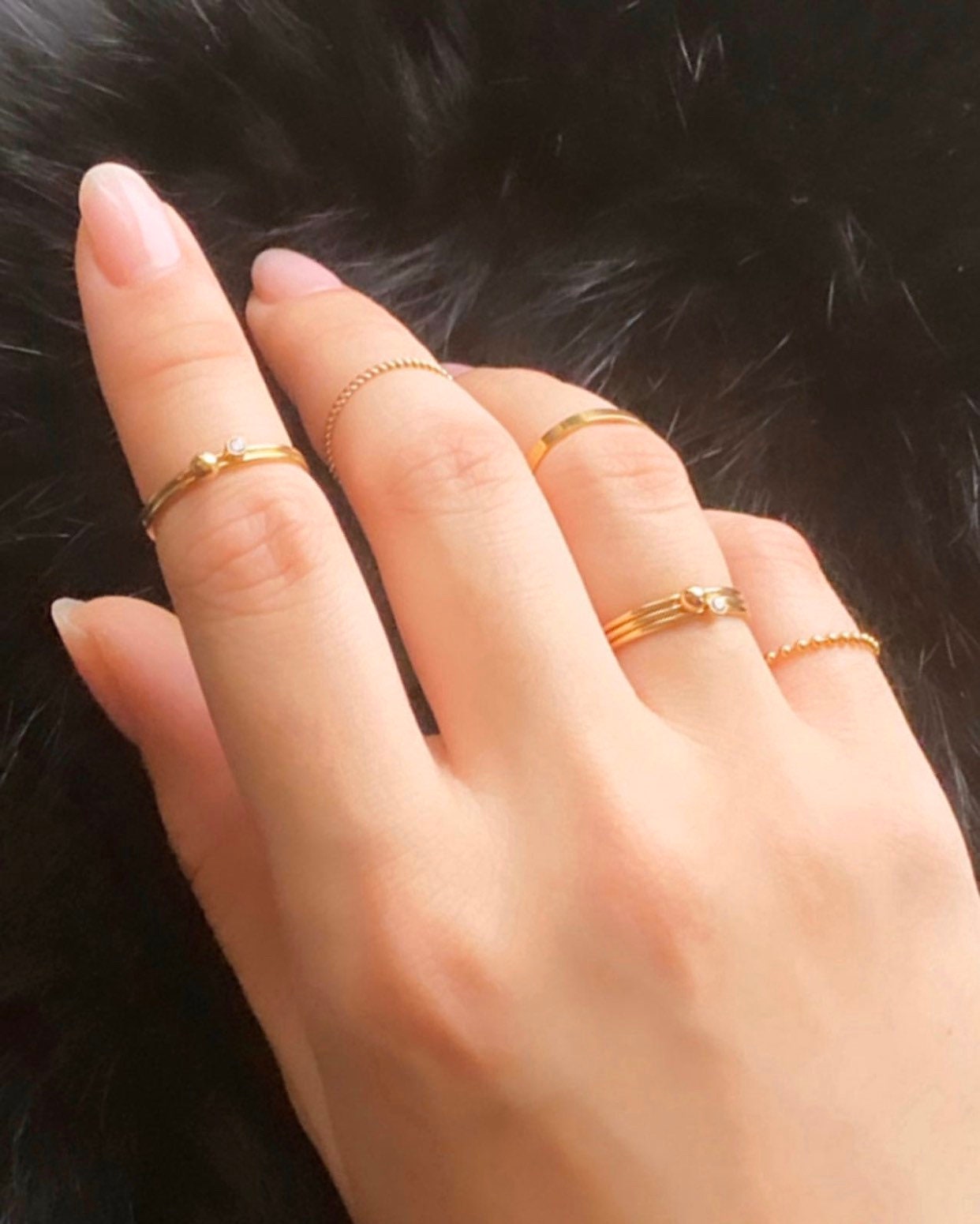 Close-up of 14K gold-filled stacking rings showing flat band, twisted rope, and pearl accent style