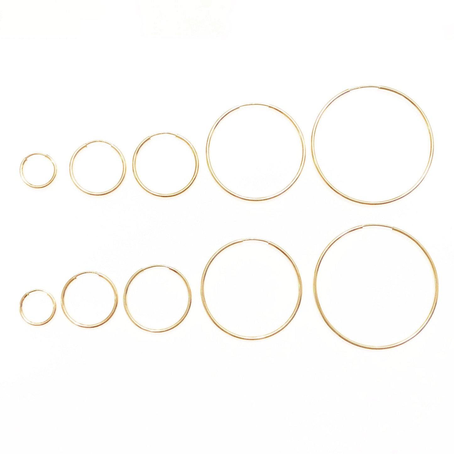 A collection of gold-filled hoop earrings in various sizes displayed on a white background.