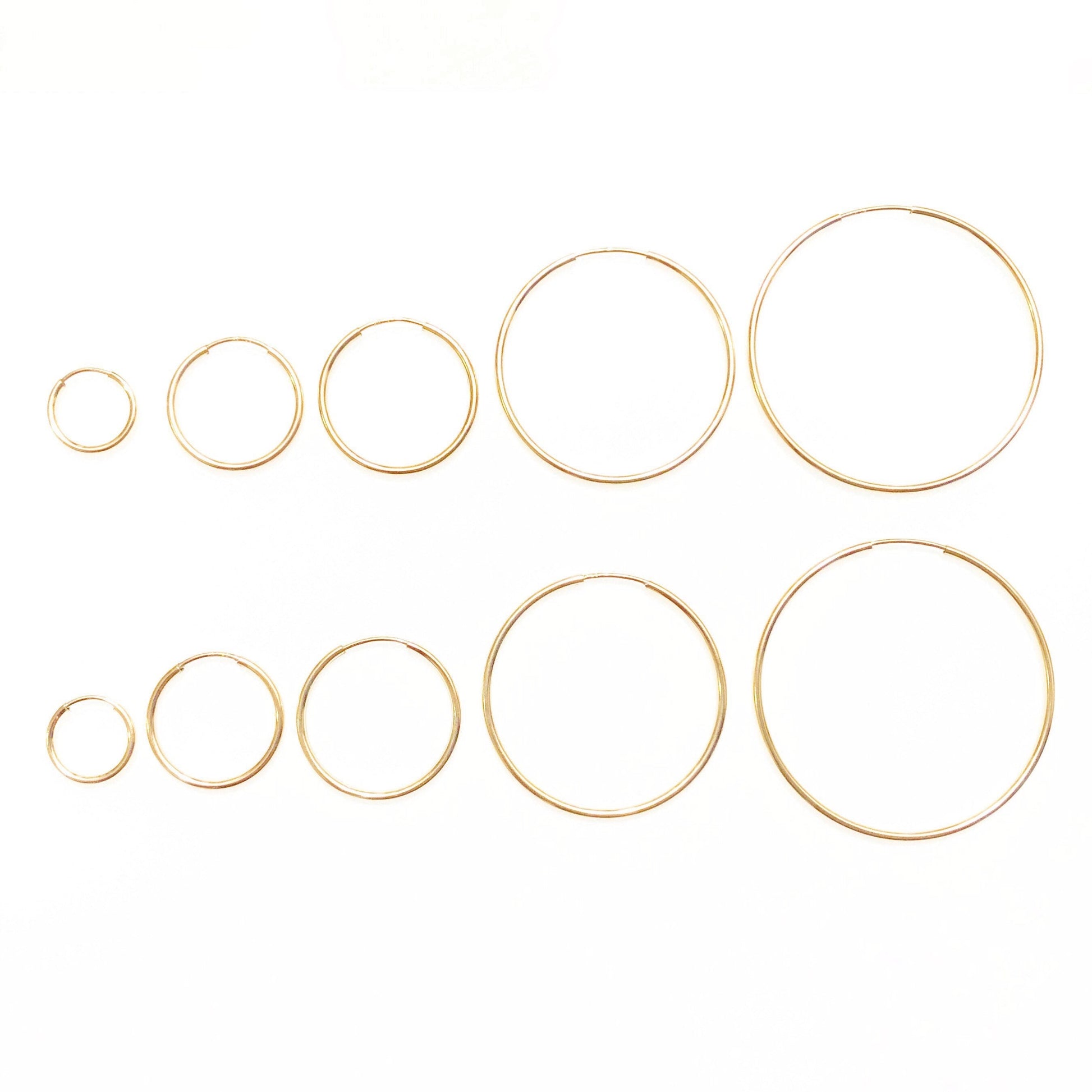 A collection of gold-filled hoop earrings in various sizes displayed on a white background.