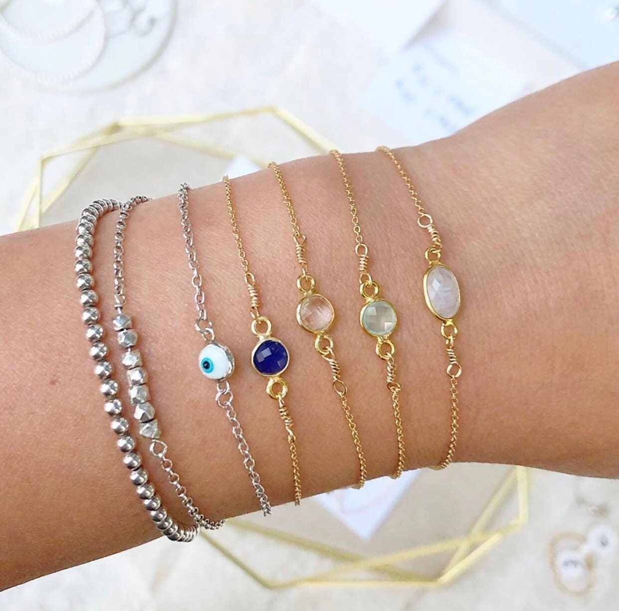 A collection of gold-filled bracelets with different gemstones displayed on a wrist.