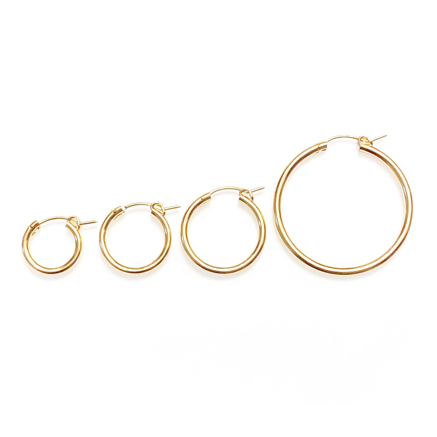 A collection of gold-filled hoop earrings in various sizes, displayed side by side on a white background.