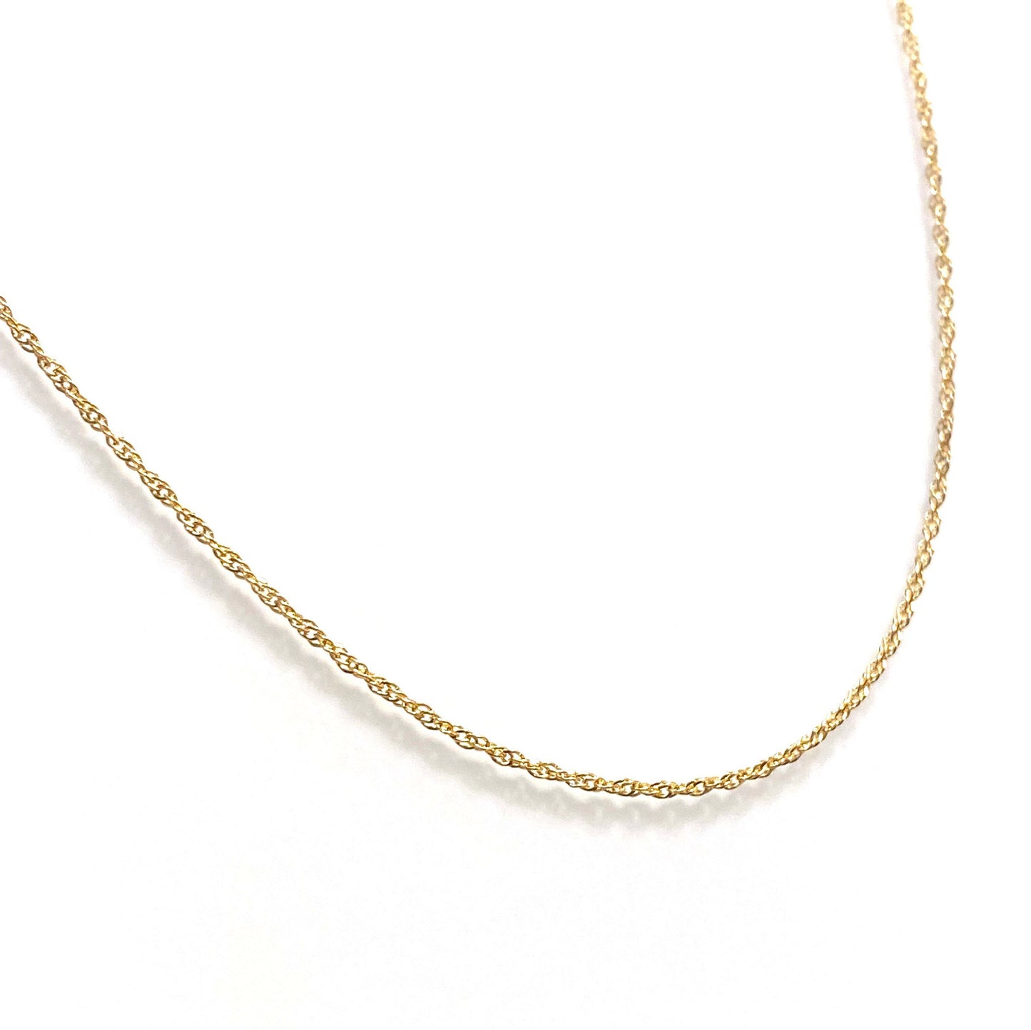 A gold-filled twisted chain necklace laid out on a plain surface.