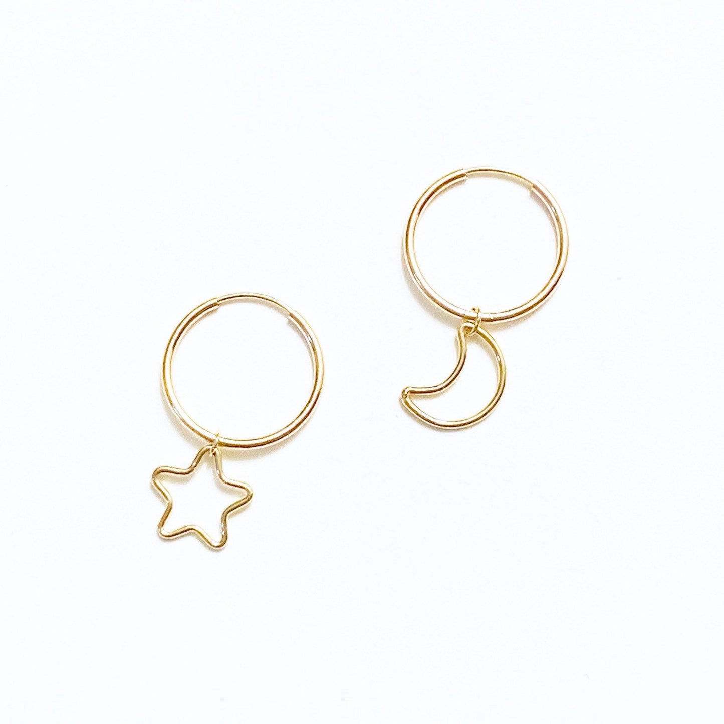 A pair of gold-filled hoop earrings, one with a dangling star charm and the other with a dangling moon charm.