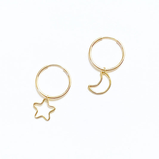 A pair of gold-filled hoop earrings, one with a dangling star charm and the other with a dangling moon charm.