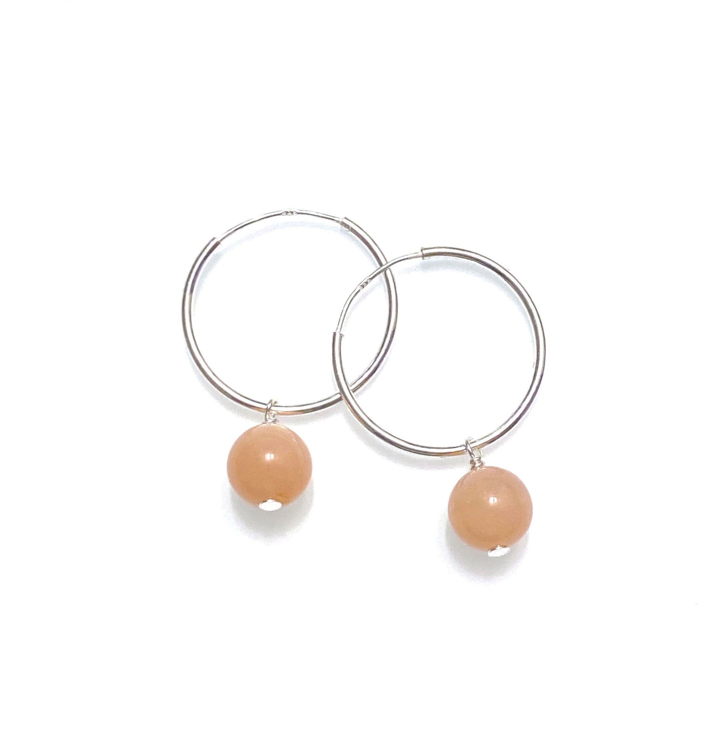 close up of peach moonstone on silver hoops