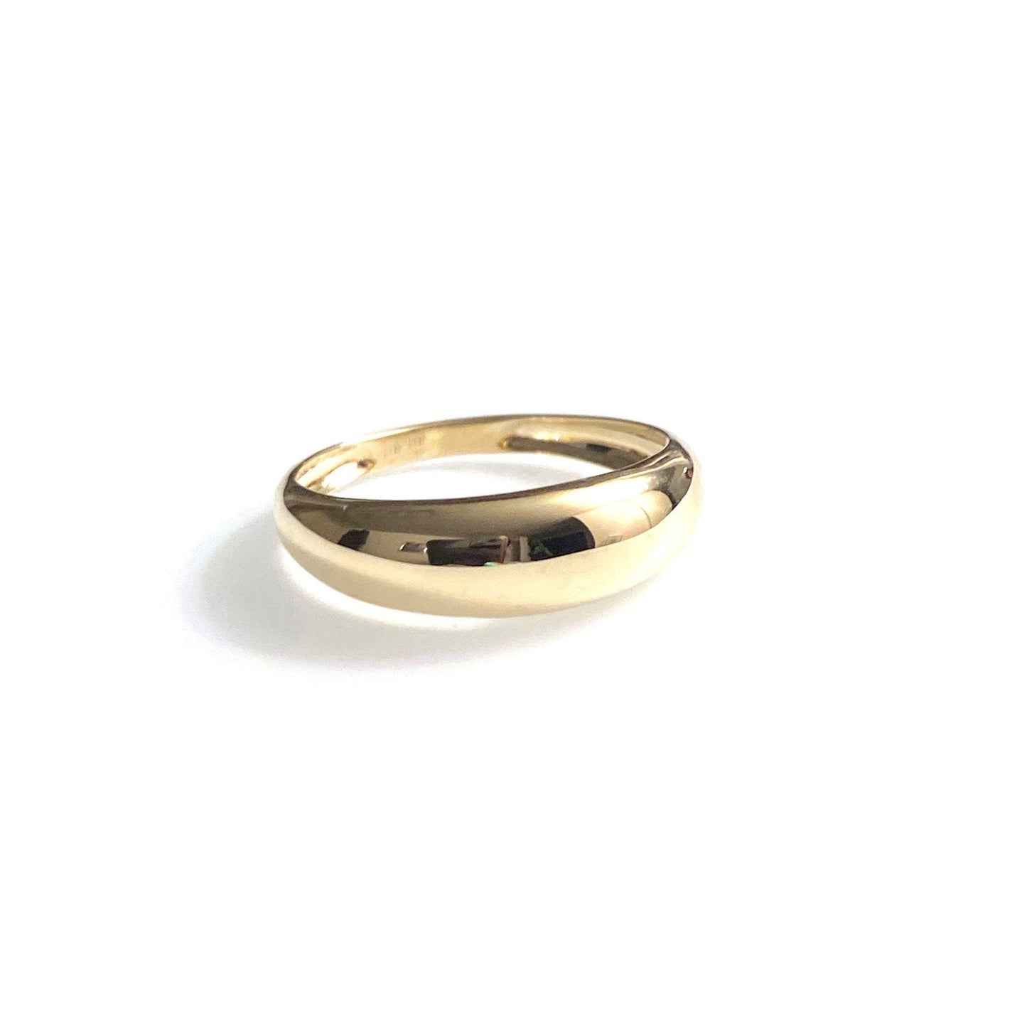 A simple gold band ring on a white background.