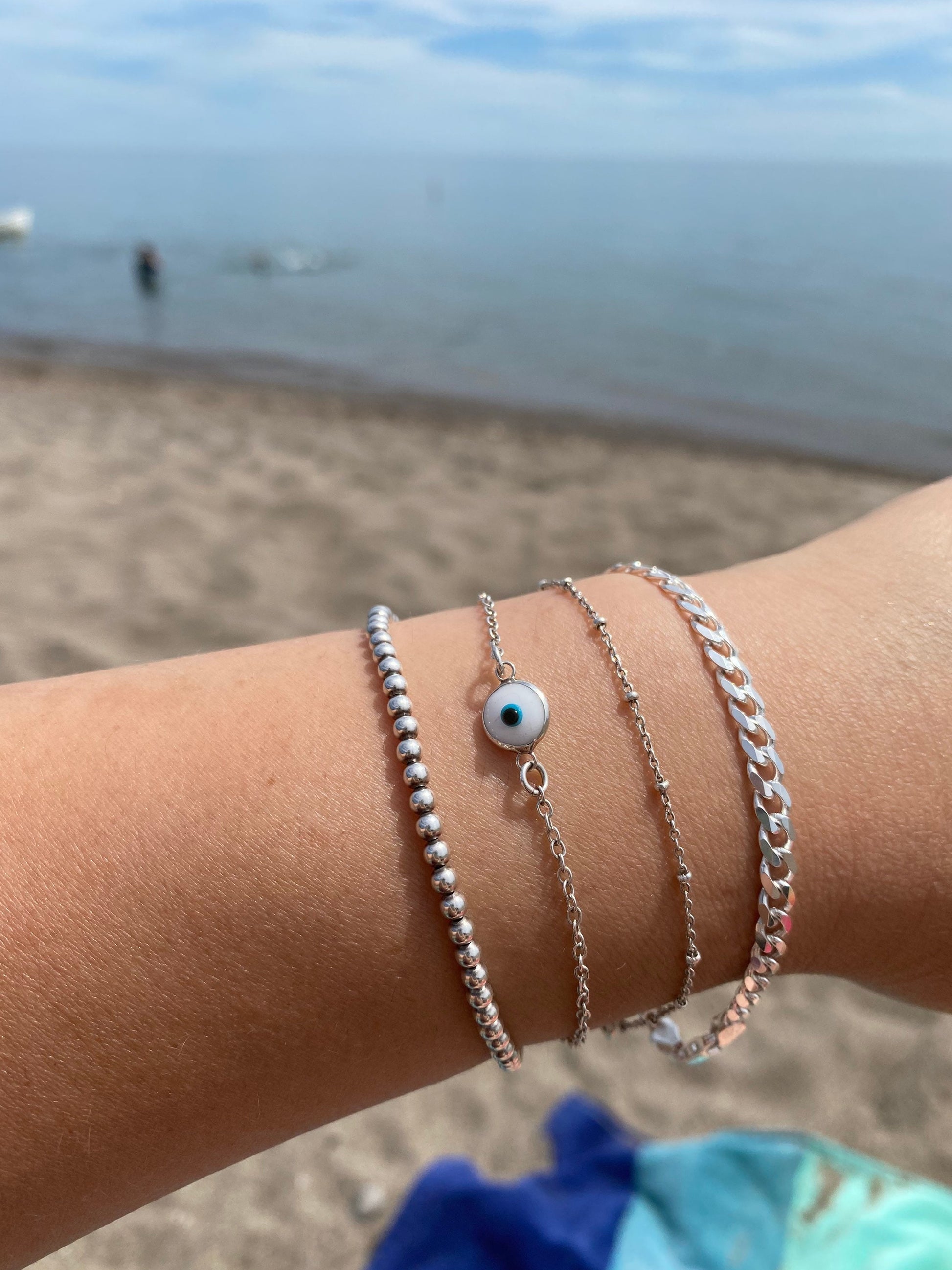 sterling silver curb chain bracelet stacked with ball evil eye and satellite chain bracelets