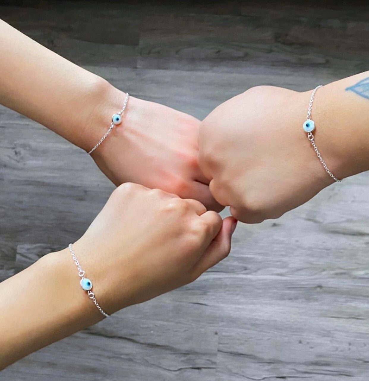 sterling silver evil eye bracelets on wrist of three besties