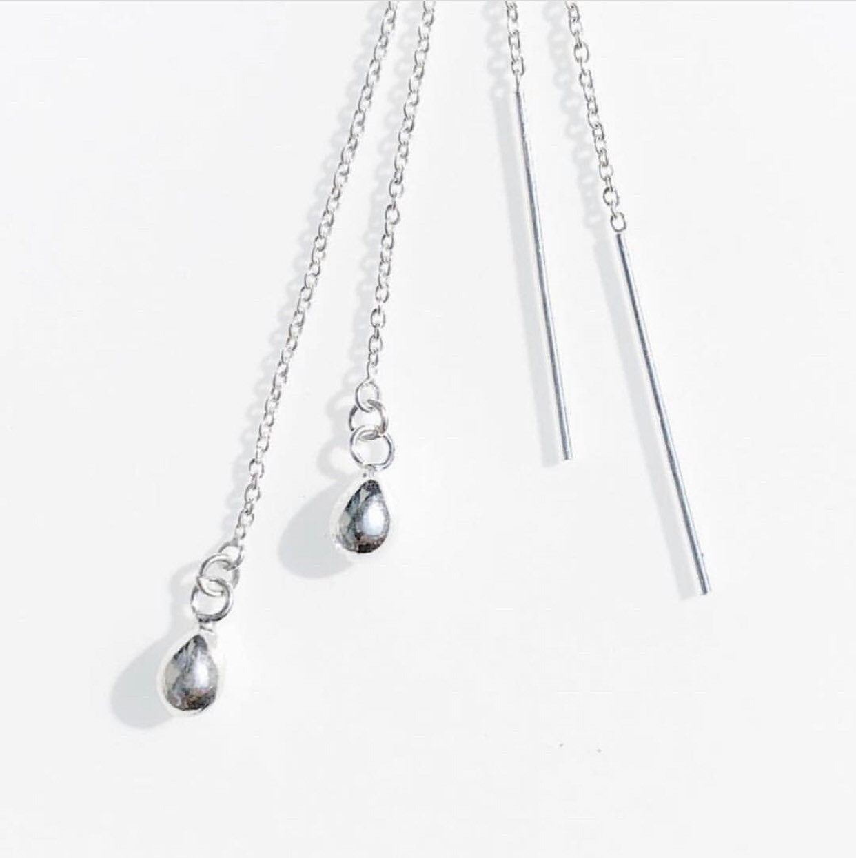 A set of sterling silver threader earrings with raindrop, art deco, star, and moon designs against a white background.